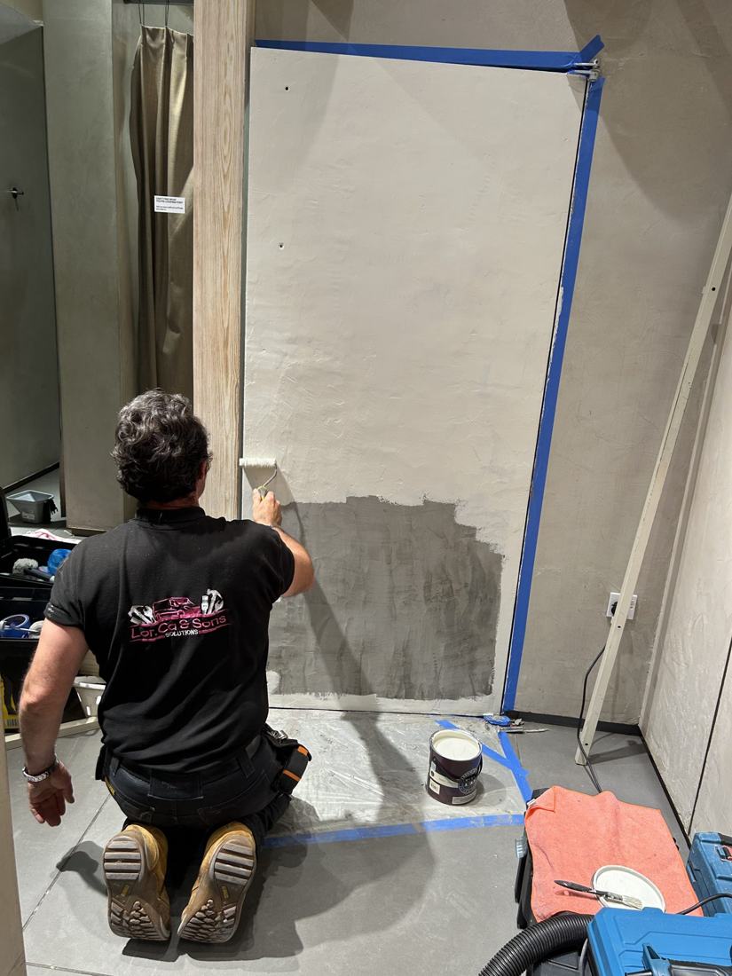 Pintor aplicando la primera capa en una pared nueva de pladur en una tienda