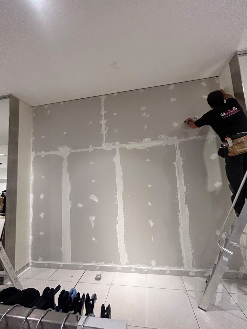 Plasterer finishing drywall joints in a commercial unit